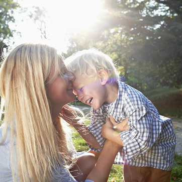 Eine Mutter und ihr Sohn kuscheln draußen in der Natur, um ihren Vitamin D Speicher in der Sonne zu füllen. 